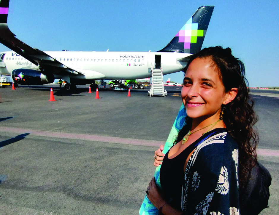 Chica yogui abordando un avión con el mat en la mano